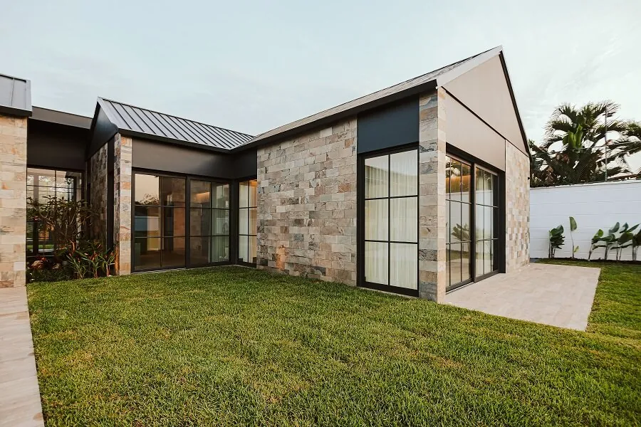 Vivienda unifamiliar con ventanas y puertas de aluminio negro y fachada de piedra