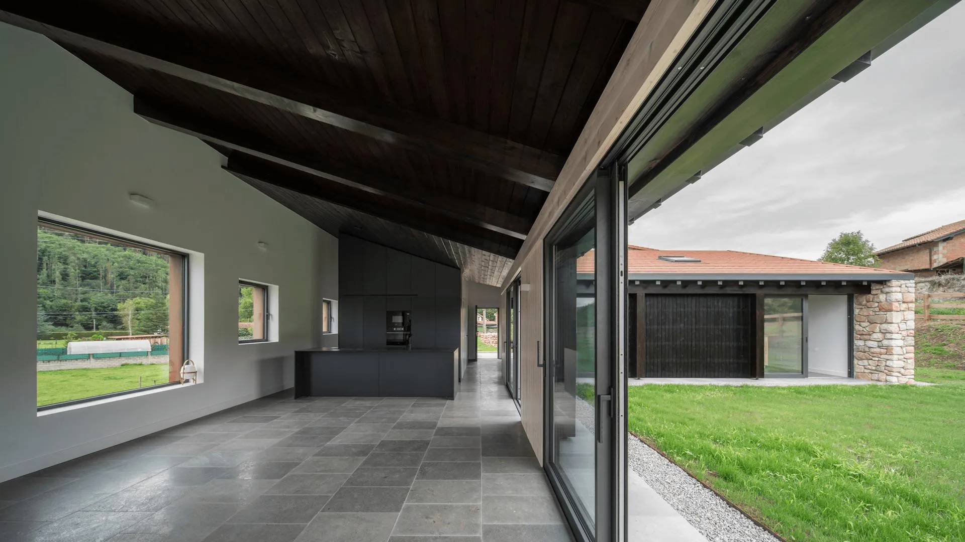 Vivienda con grandes puertas correderas de aluminio y carpintería metálica en tono oscuro