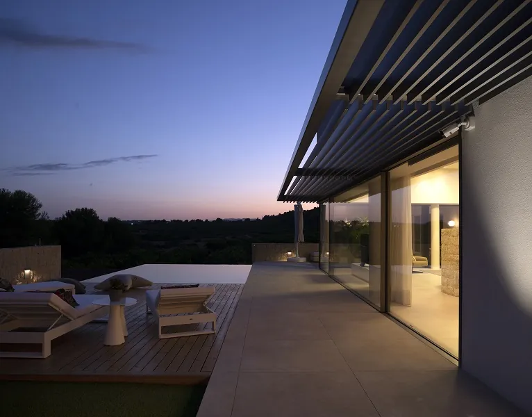 Pérgola de lamas de aluminio sobre terraza de vivienda al anochecer